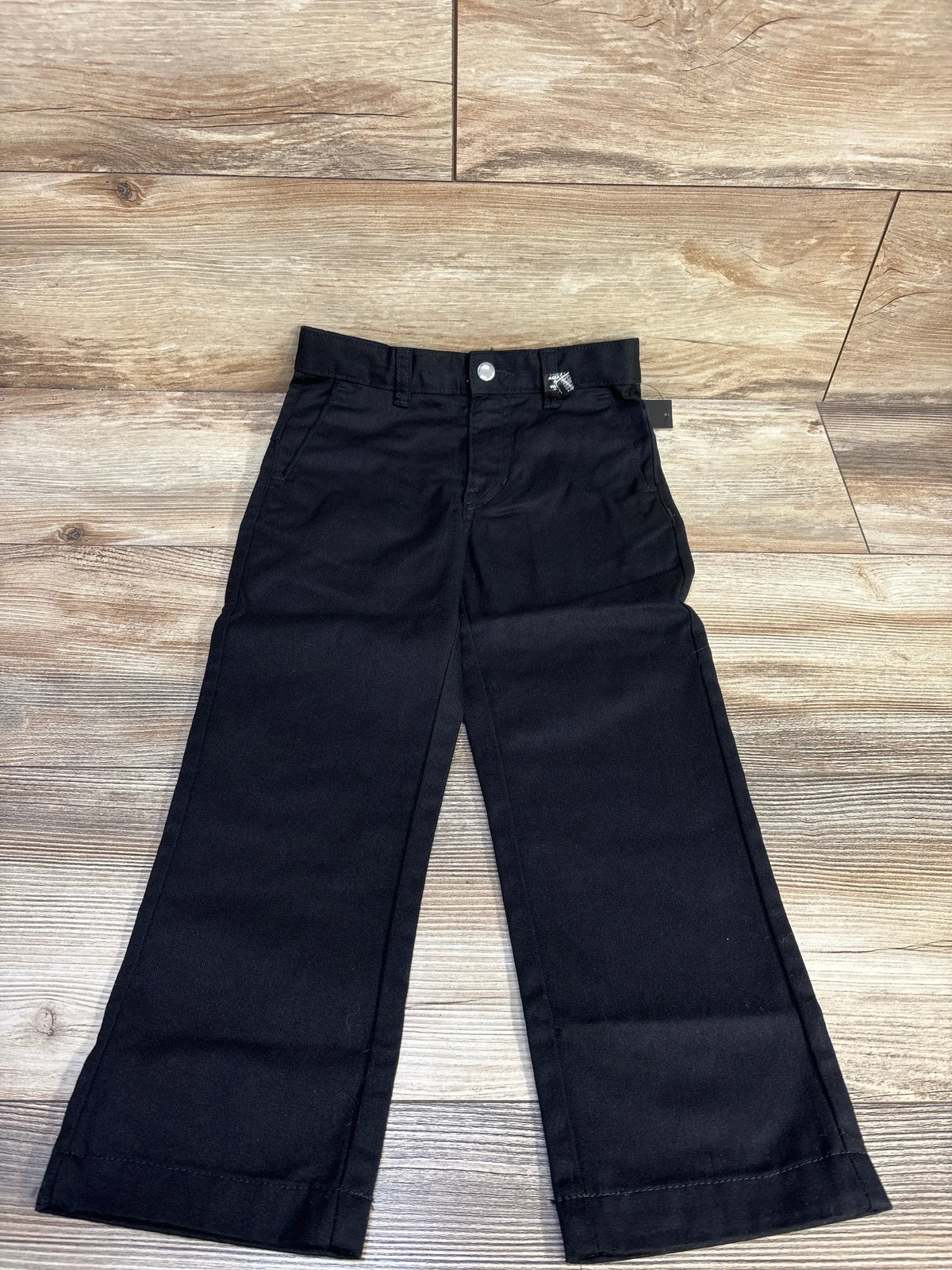 Front view of new Volcom VMonty pants in black, size 5T, showcasing belt loops, front pockets, button closure, and straight legs on a wood floor