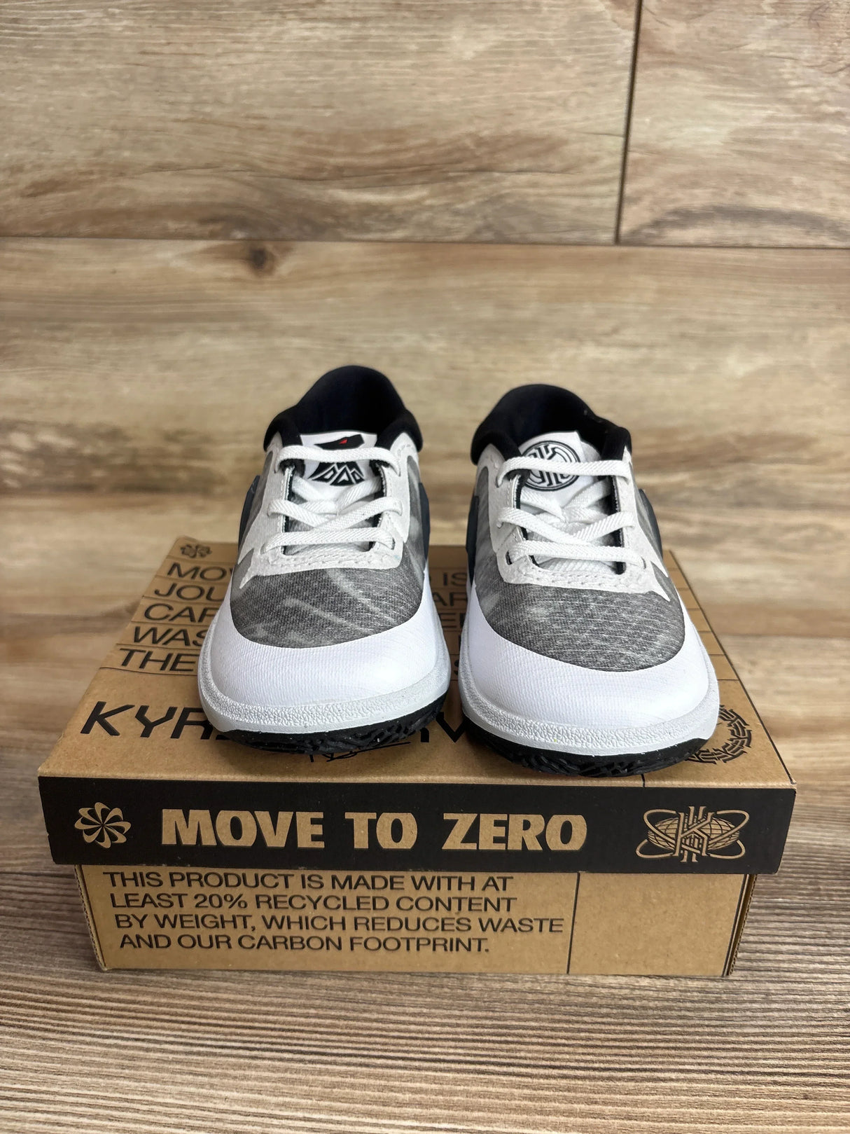 Front view of Nike Kyrie 8 TD toddler sneakers (size 9C) showing white and gray upper, black collar and laces on a Move to Zero cardboard box with wood background