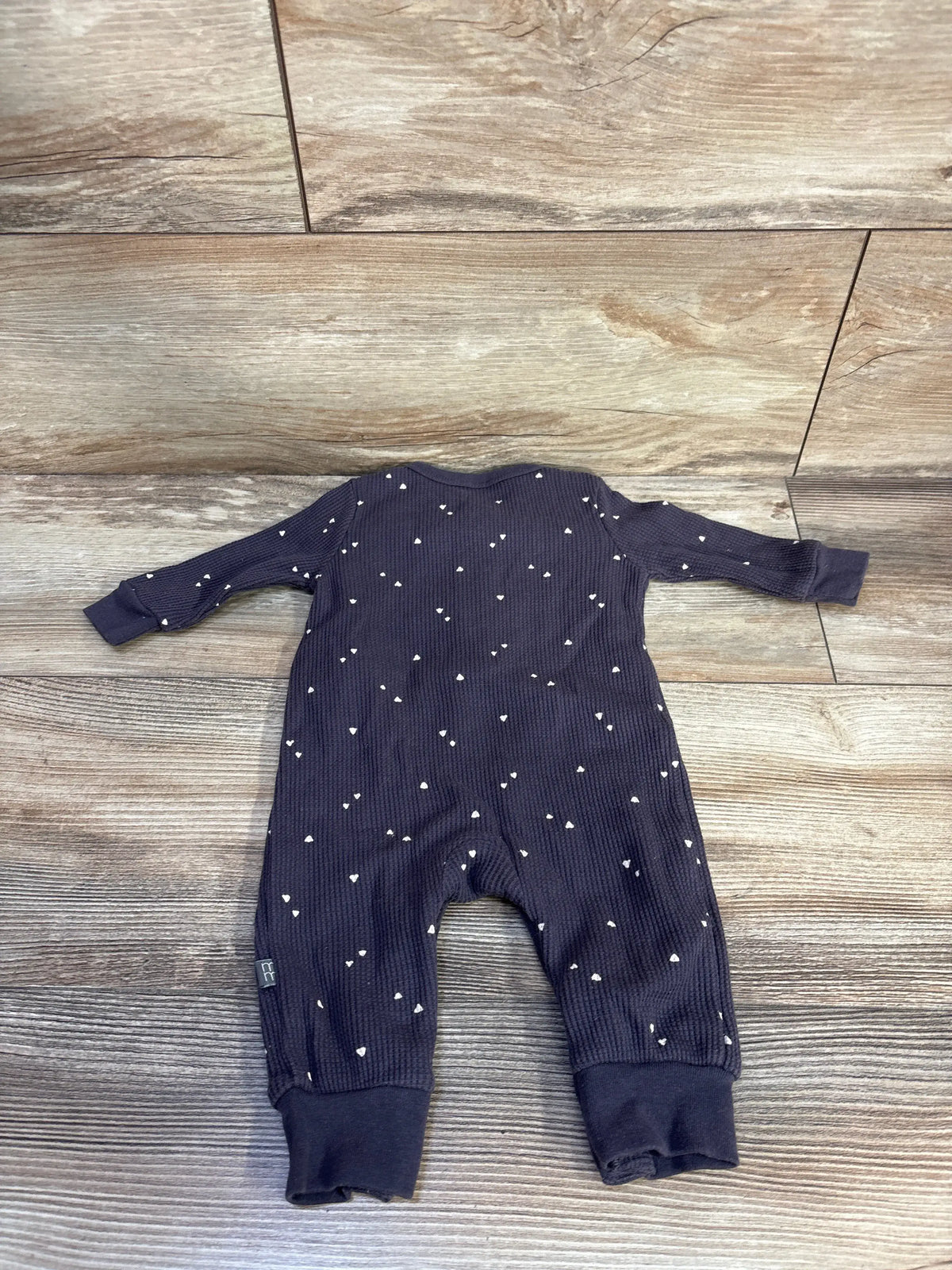 Front view of Modern Moments grey waffle knit henley coverall with long sleeves and white heart pattern on wood floor