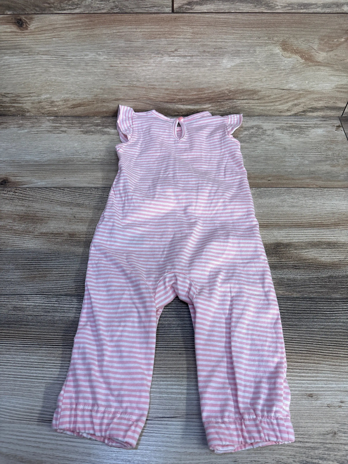 Top-down view of Simple Joys pink striped ruffle jumpsuit showcasing ruffled neckline and leg hems on a wood background