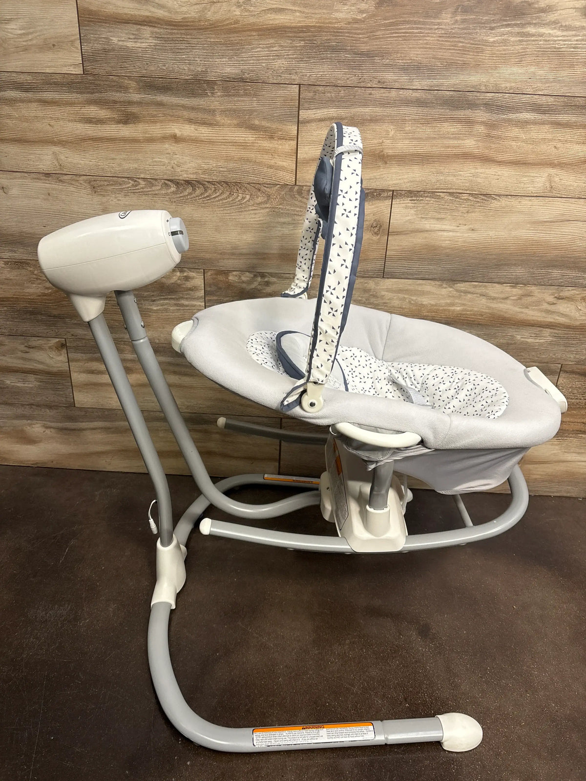 Front view of Graco Soothe ‘n Sway LX Swing with Portable Rocker showing padded seat on wood flooring