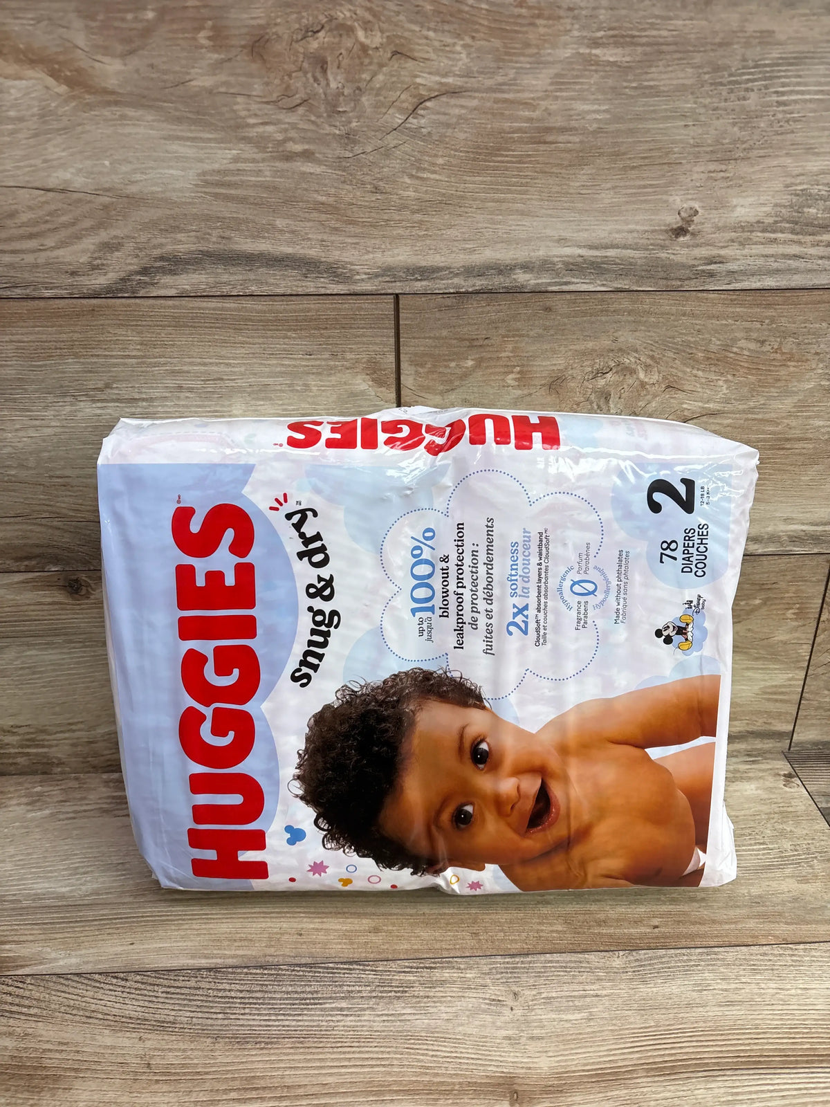 Front view of Huggies Snug and Dry diapers size 2 package showcasing 78 diapers on a wood floor