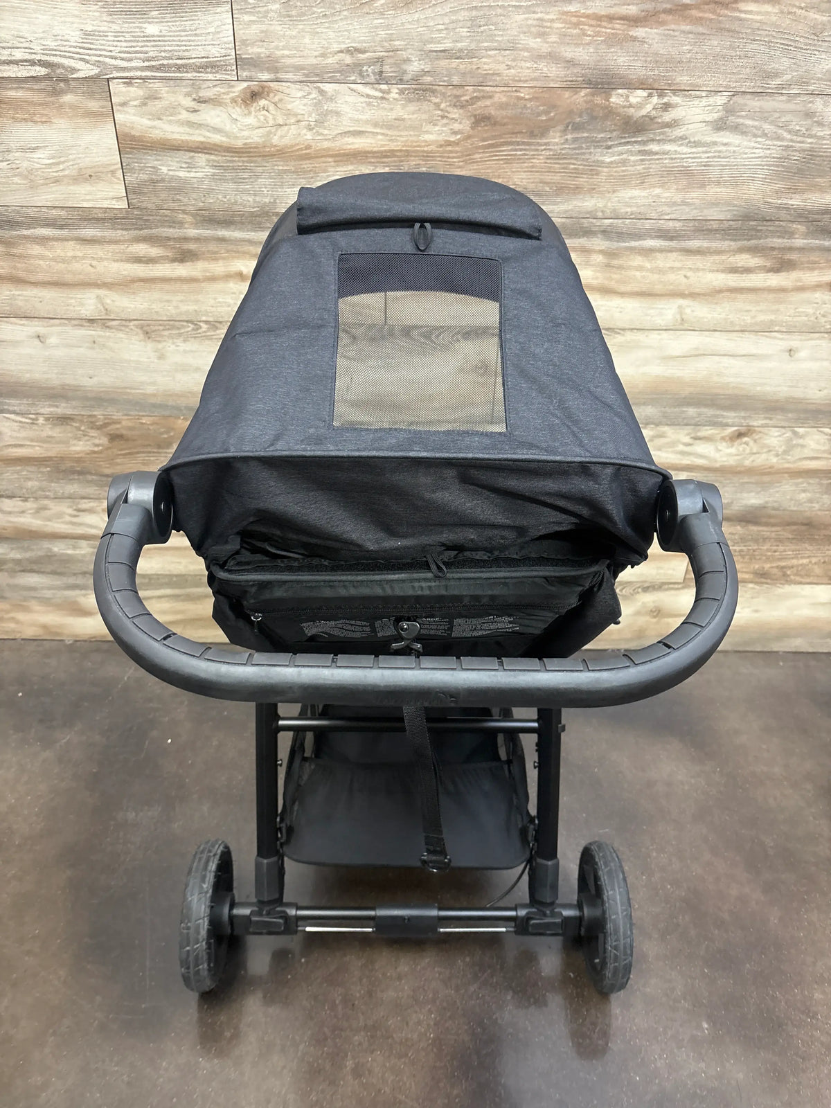 Rear view of Baby Jogger City Mini GT2 All Terrain Stroller in Opulent Black with mesh canopy window on wood flooring