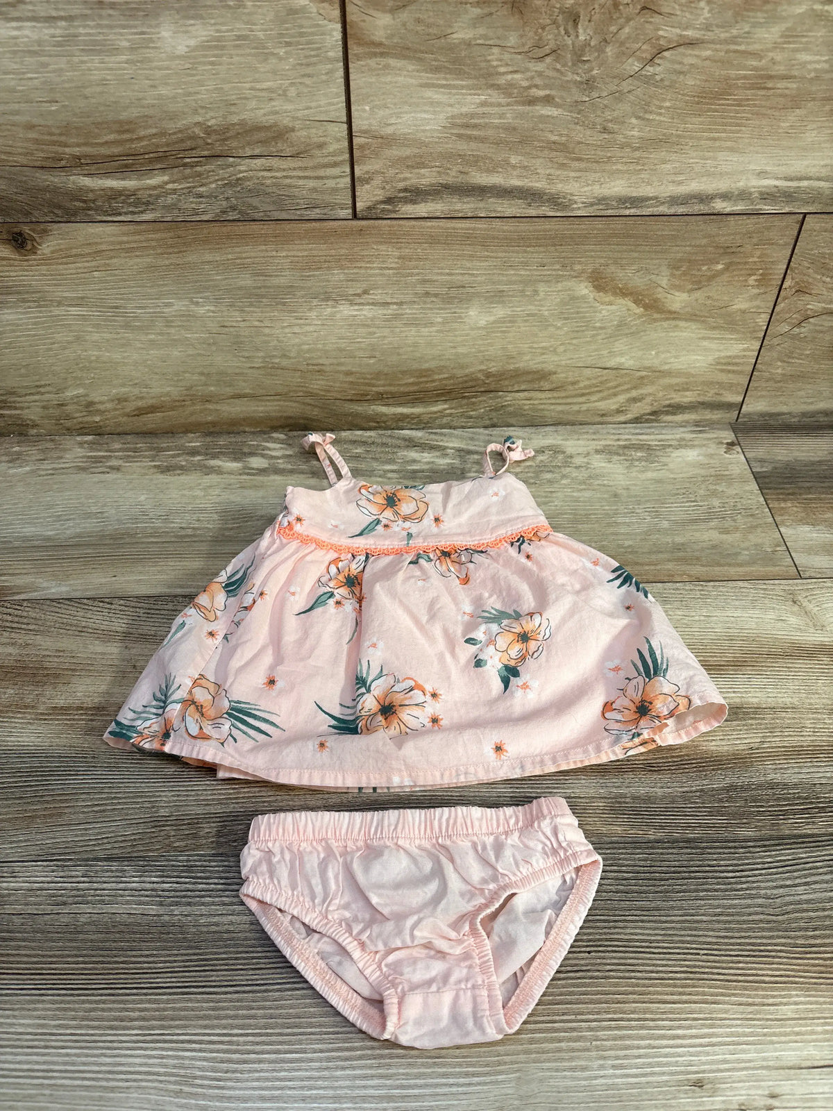 Front view of Oshkosh two-piece floral tank top and bloomers set showcasing pink floral print on a wood floor