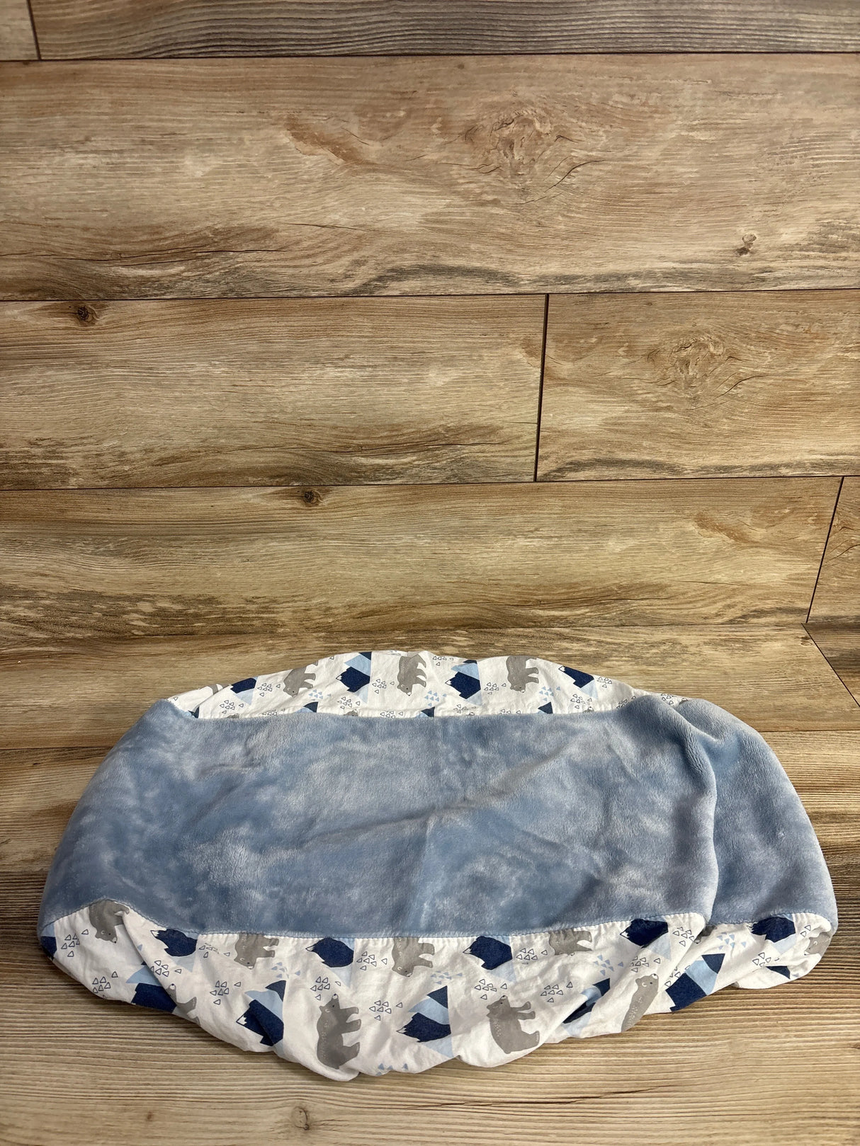 Soft blue and white baby blanket with bear and mountain print on wooden floor