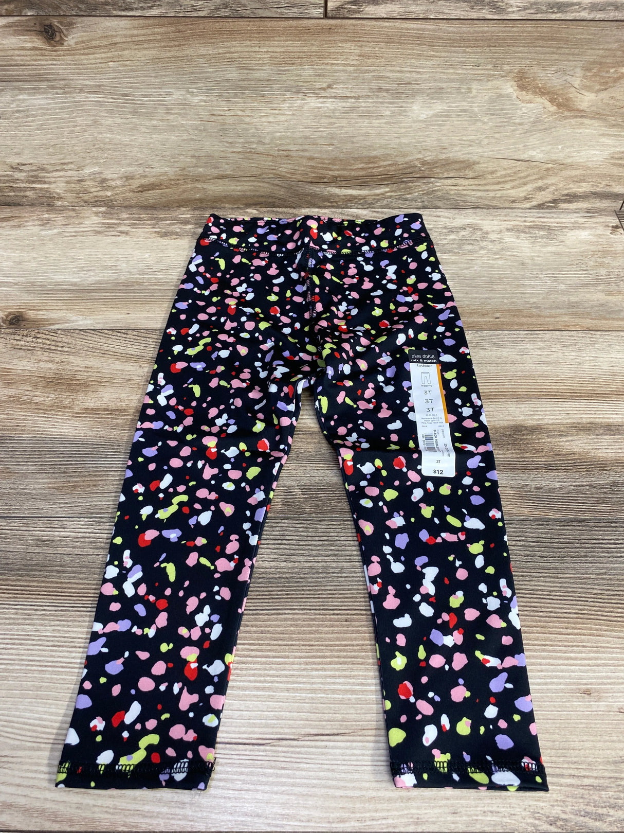 Toddler leggings with vibrant multicolor splatter print on black background, size 3T, $12 price tag