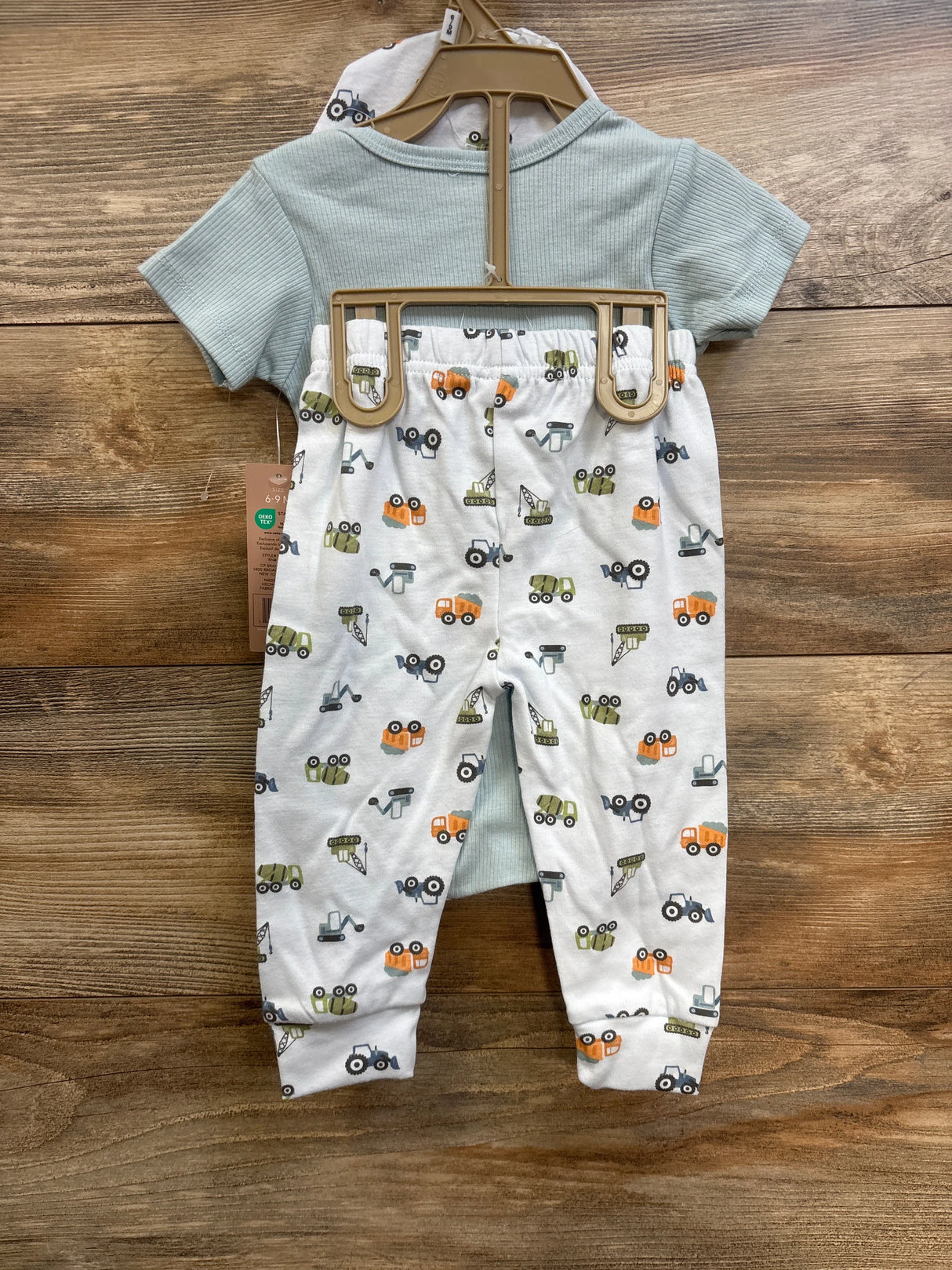 Front of Chick Pea 3-piece Dad’s Little Helper set with ribbed blue bodysuit and white truck-print pants on hanger against wood