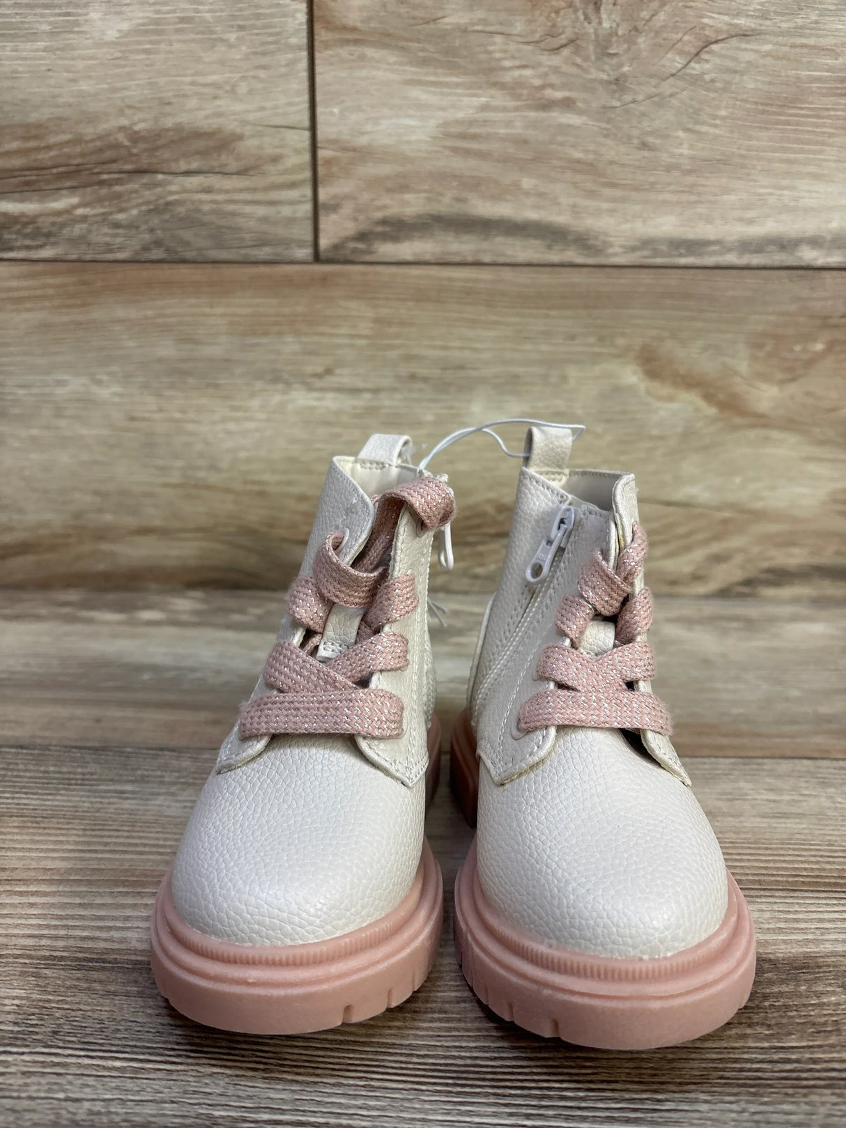 Front view of Cat & Jack Amaya toddler zipper combat boots showing cream textured upper, pink chunky sole and pink laces on wooden background