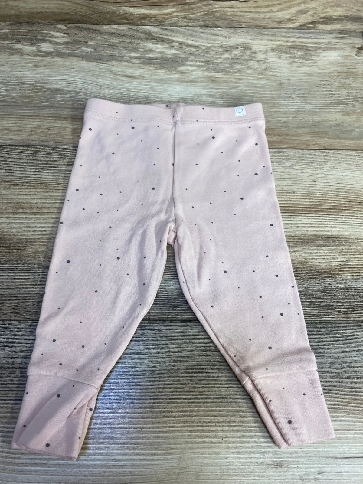 Baby pink leggings with small black speckle pattern on wooden floor background