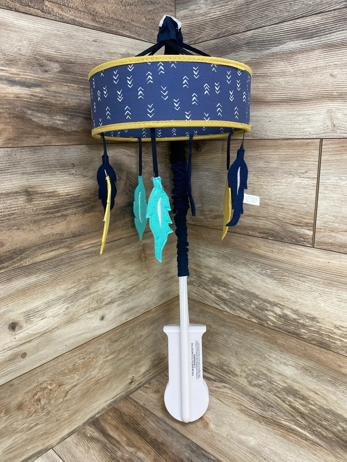 Blue and yellow hanging baby mobile with feather decorations on wooden background