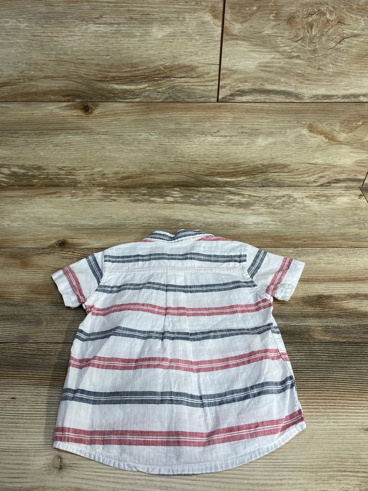 Back of short sleeve baby shirt with red and gray stripes on wood background