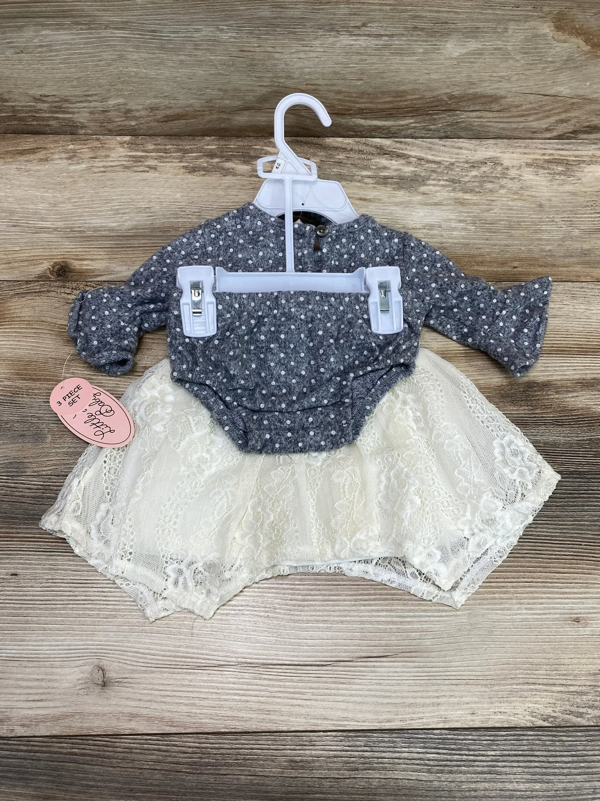 Front view of Little Lass 3-piece baby dress set size 12M showcasing grey polka-dot bodysuit with cream lace skirt on wood background