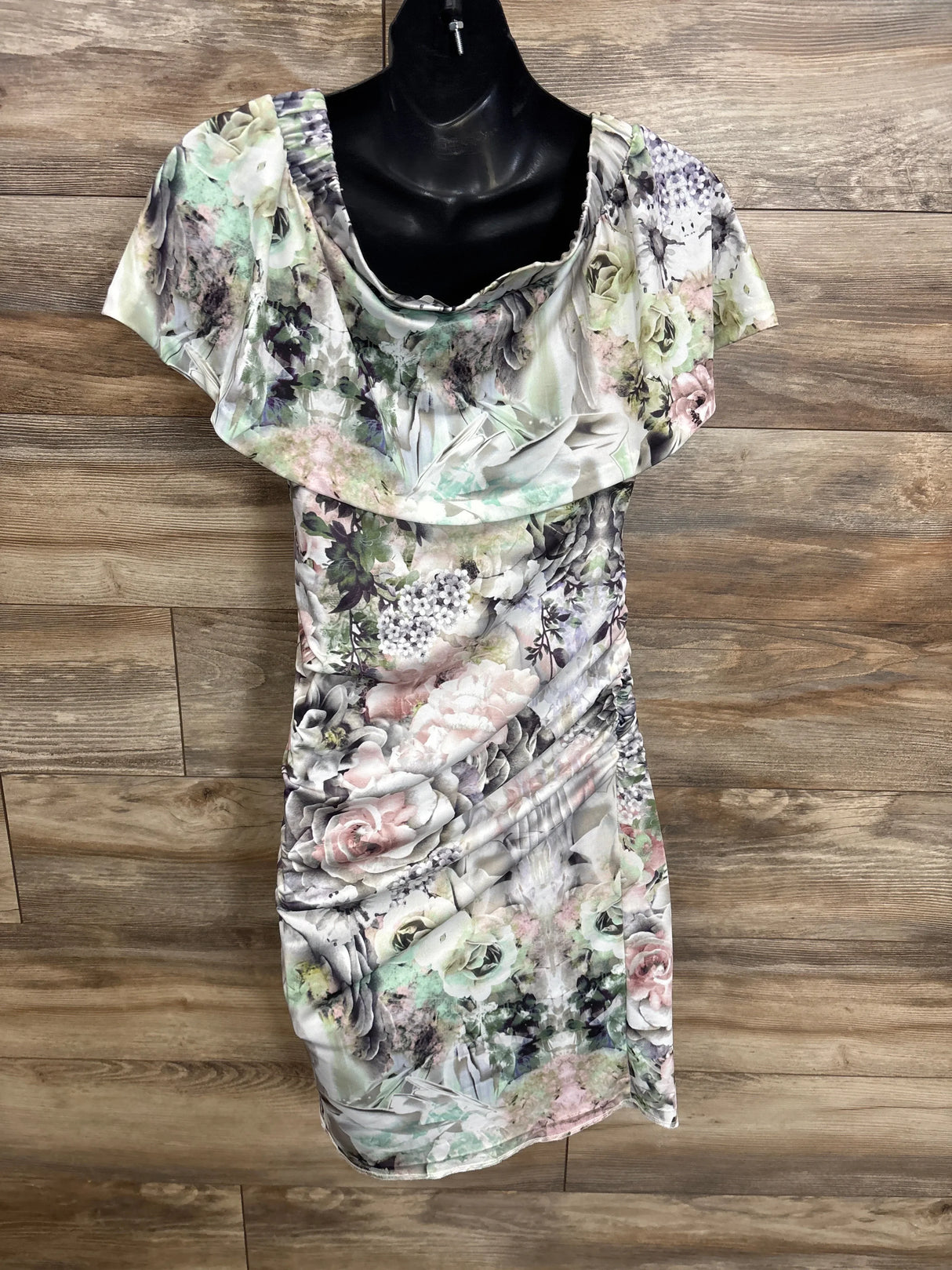 Front view of Ripe Maternity off-the-shoulder floral maternity dress in white size small showing ruffled neckline and side ruching on wood background