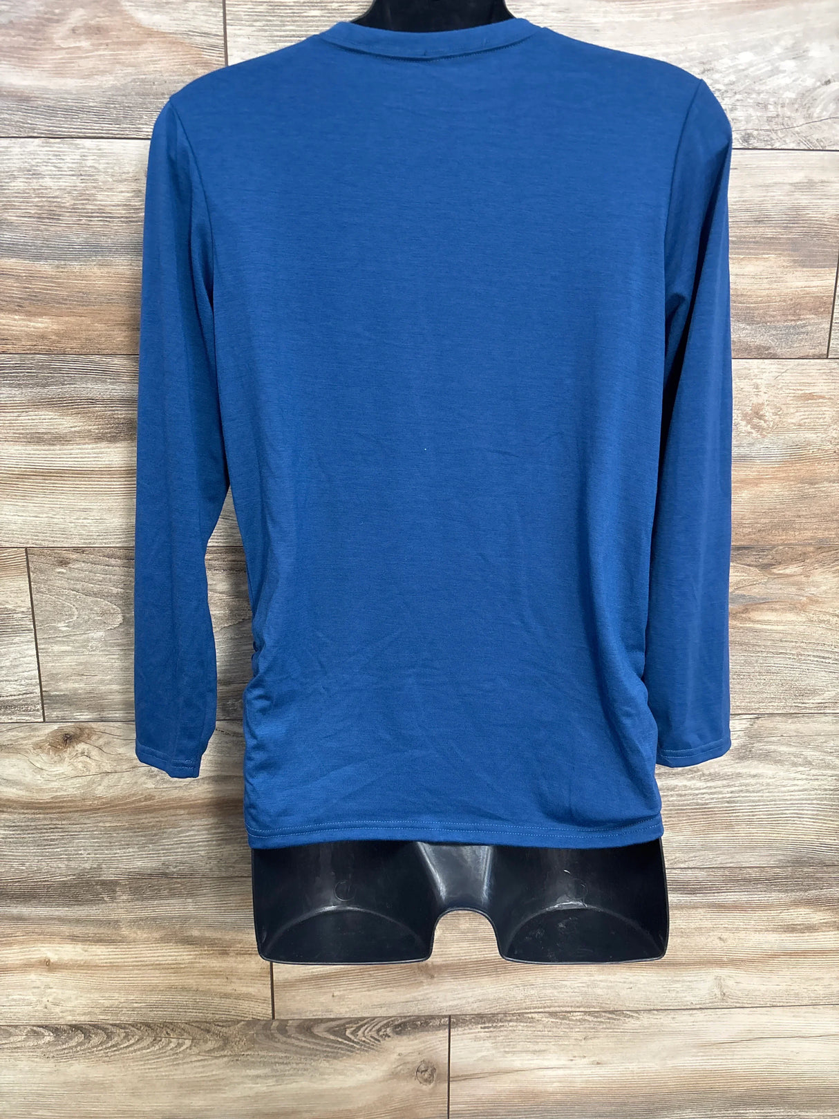 Back view of light blue maternity long sleeve shirt showcasing solid fabric on a black mannequin against a wood background
