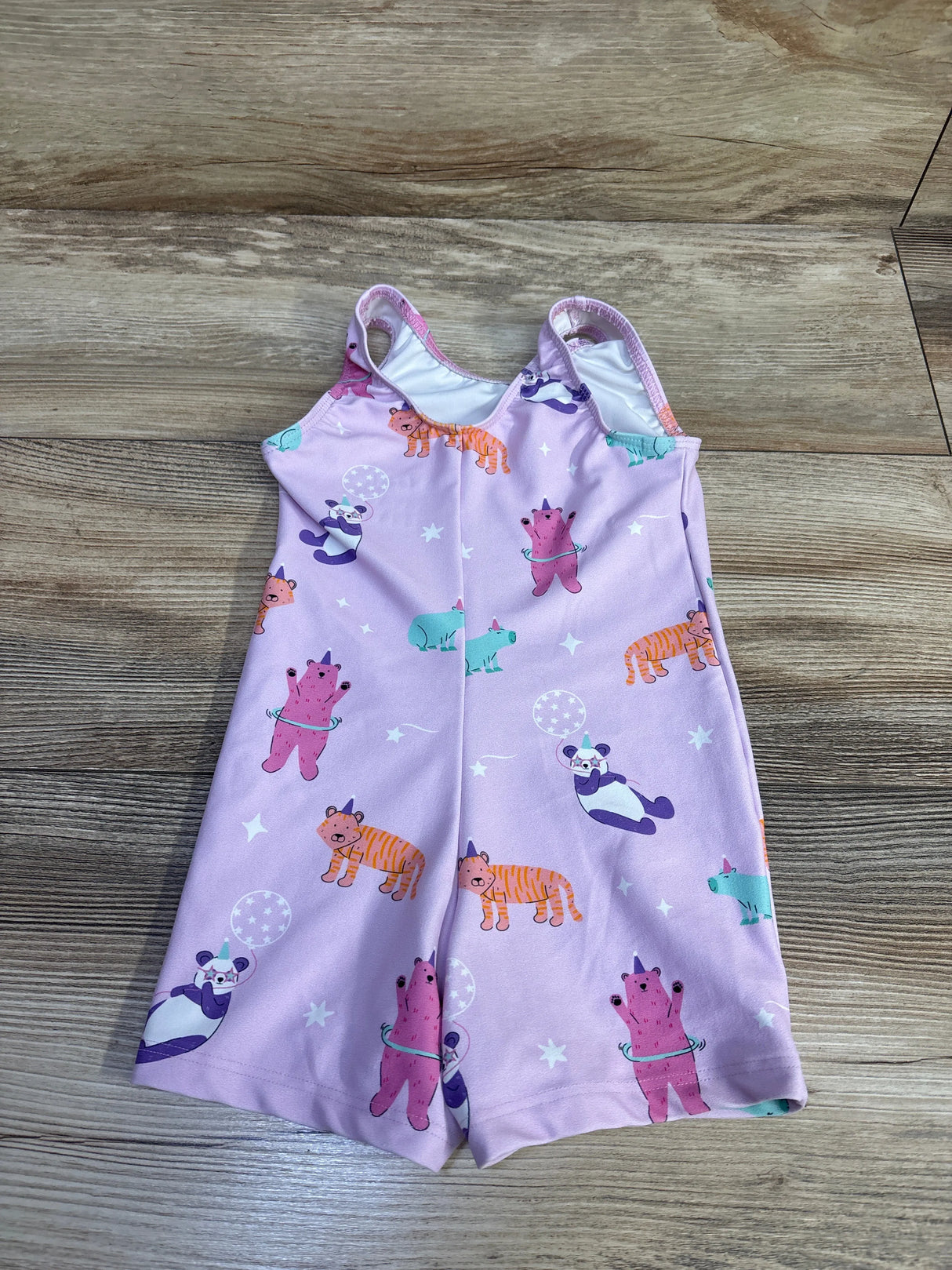 Front view of Destira toddler leotard size 2T showcasing pink animal print with bears, pandas, and tigers on a wood floor background