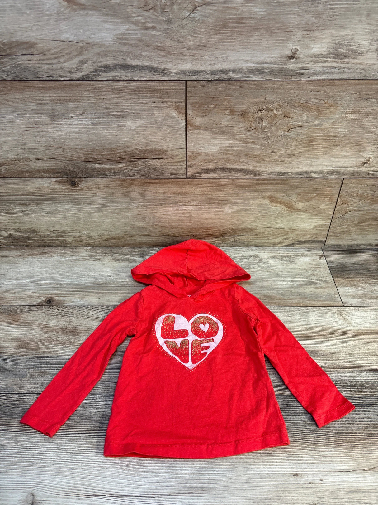 Red girls long sleeve hooded shirt with heart and LOVE graphic, laid on wooden background