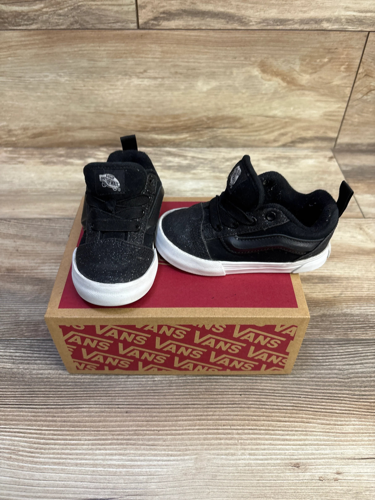 Front and side view of Vans Knu Skool toddler sneakers, black glitter upper and white rubber soles on a Vans box, size 6C