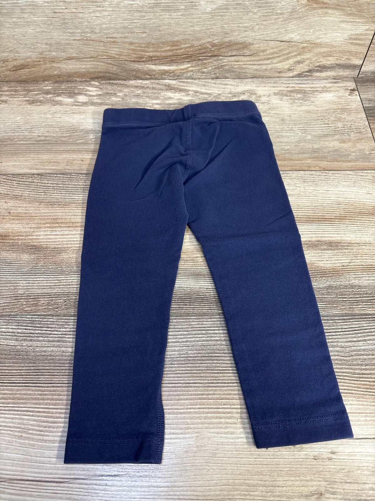 Front view of Primary Leggings Navy sz 2T showcasing full-length legs and elastic waistband on a wood-look floor