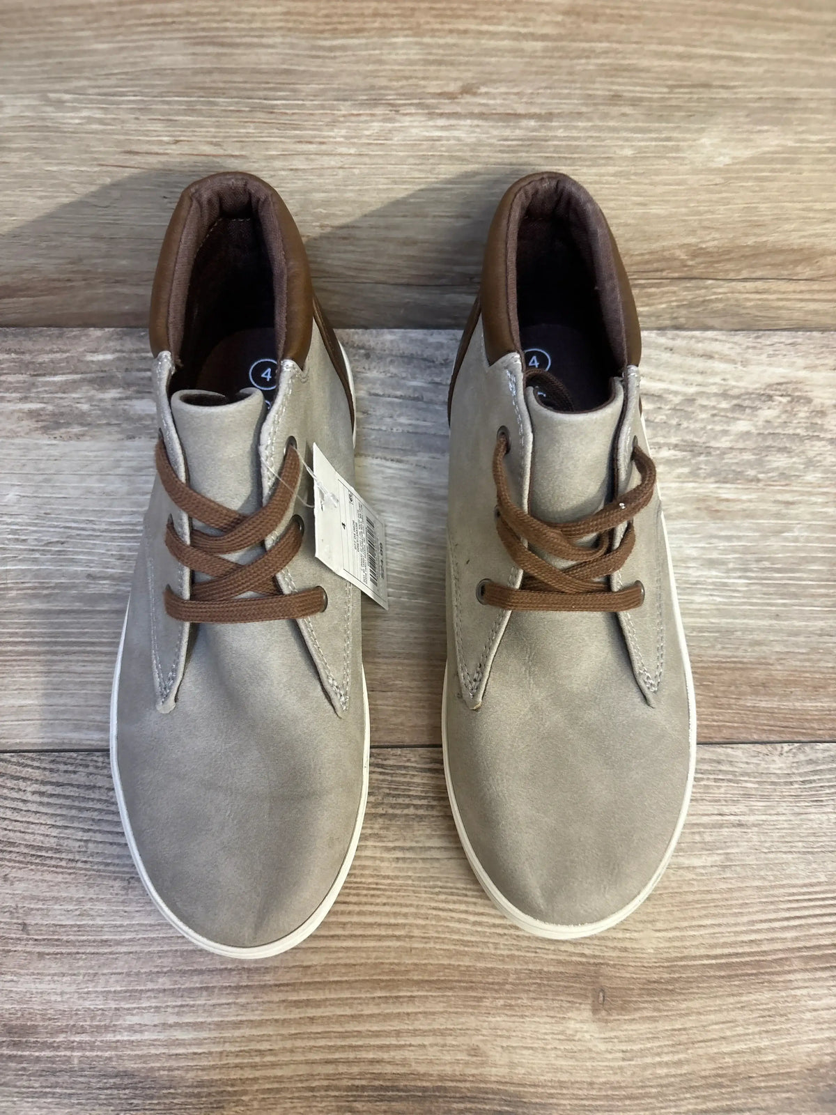 Top view of Cat and Jack Jakob toddler boots size 4Y showcasing grey-beige upper, brown collar and laces, white sole on wood background