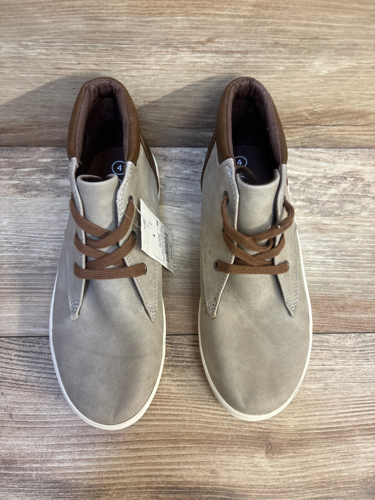 Pair of toddler size 4 beige and brown lace-up shoes on wooden floor