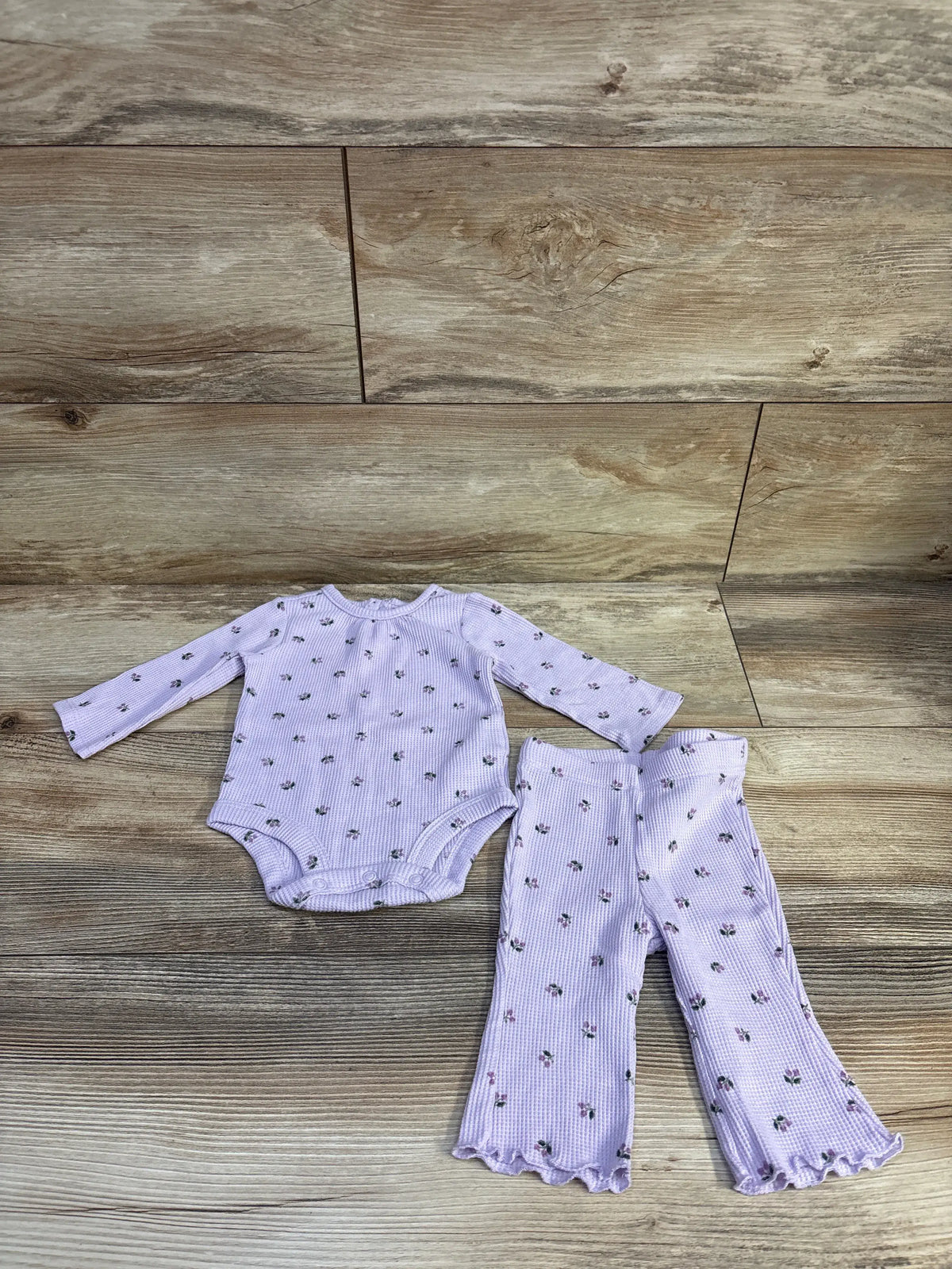 Front view of Carter’s 2pc Floral Waffle Knit Bodysuit & Pants Set in pink with long sleeves and ruffled hems on wood background