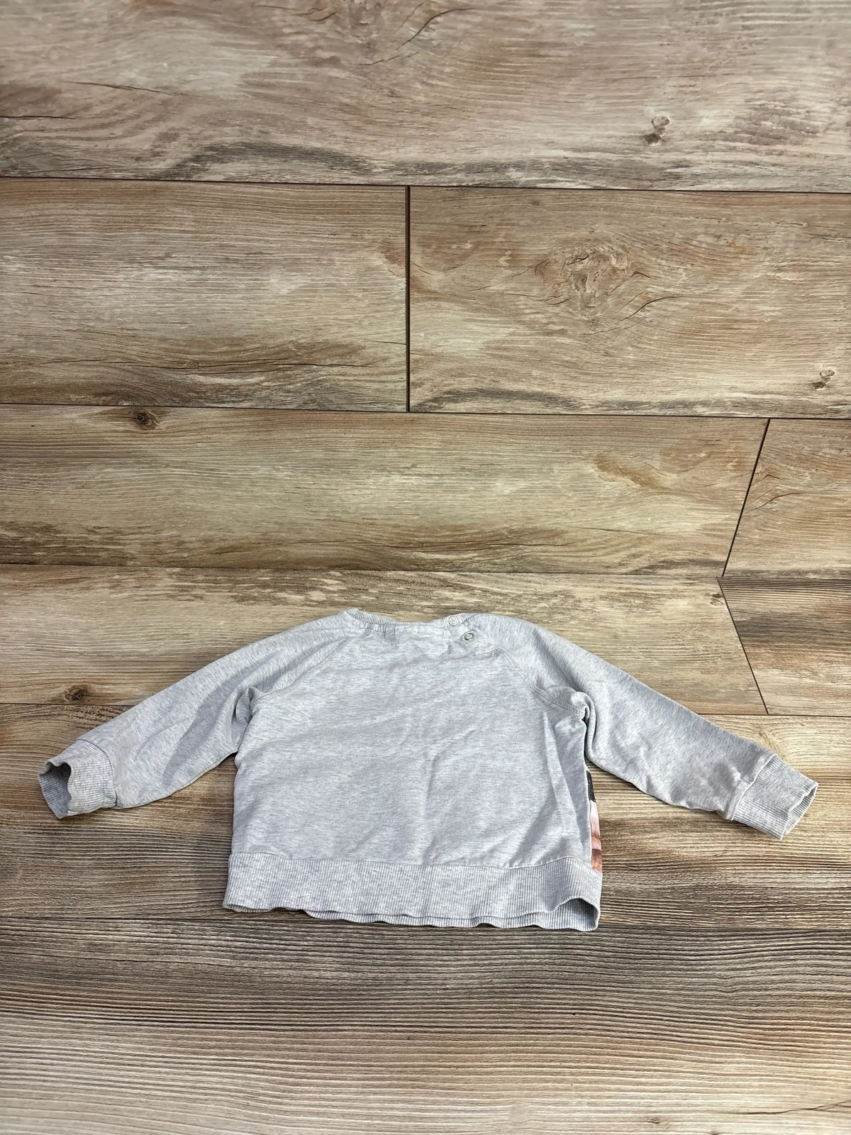 Back view of Molo Cat pullover sweatshirt in grey size 12-18 months showcasing shoulder snap button closure on wooden background