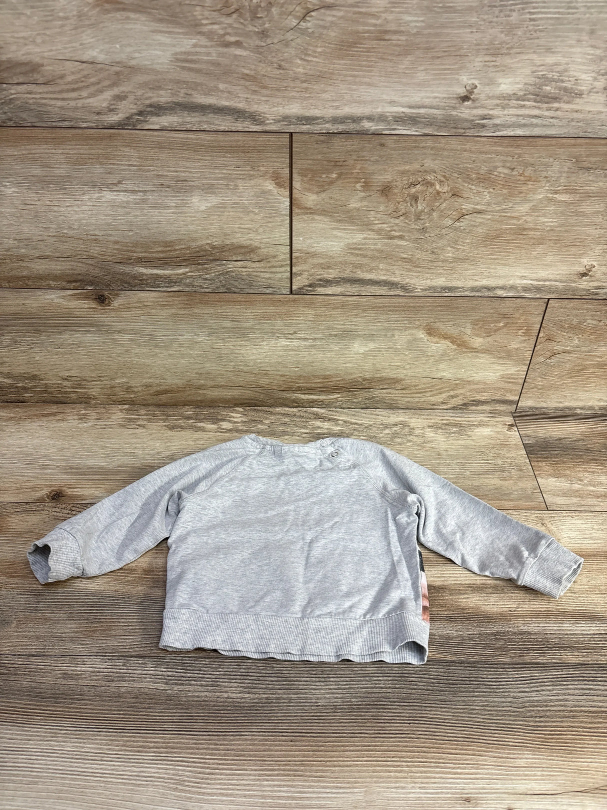 Gray long sleeve baby shirt with button detail on wooden background