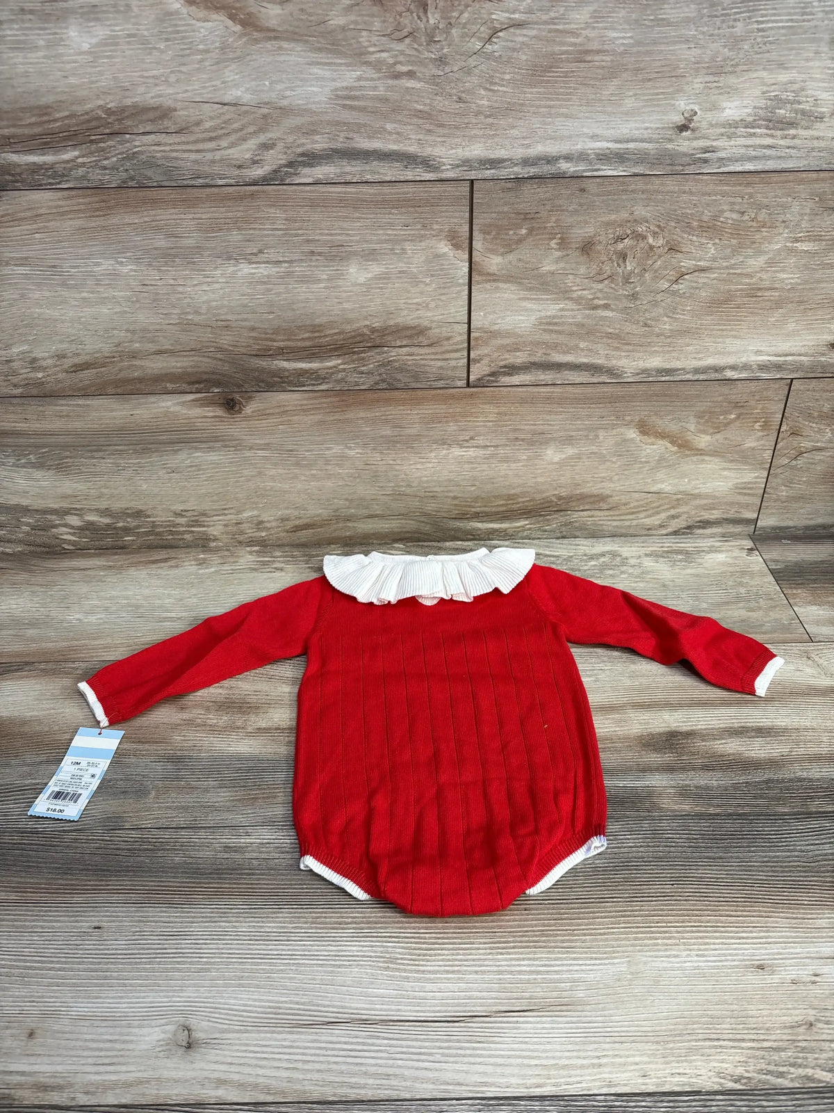 Red long sleeve baby romper with white ruffle collar on wood background