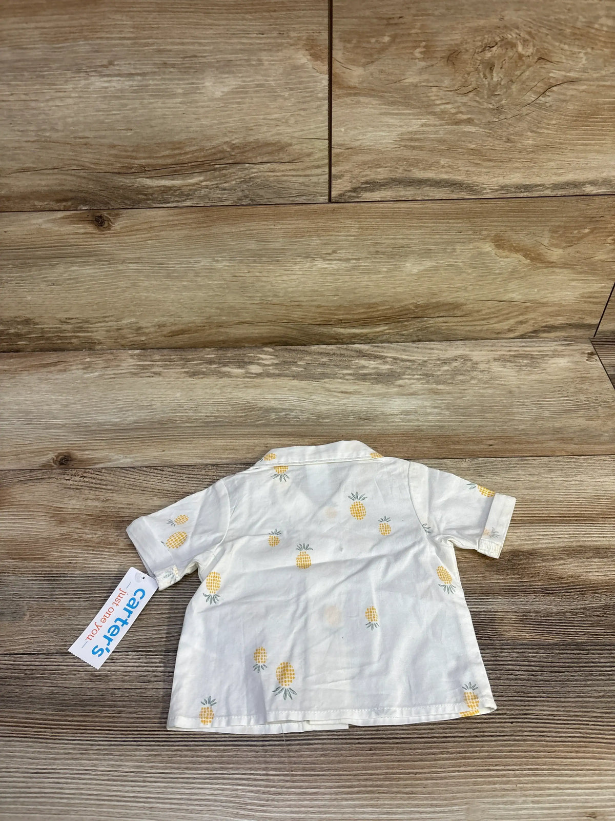 Back view of Just One You newborn white pineapple button-up shirt showcasing short sleeves and pineapple print on a wood floor