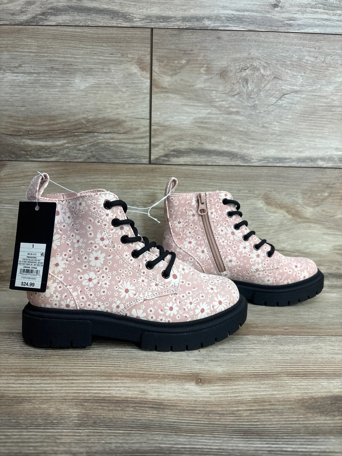 Pink floral kids boots with black laces and chunky soles on wood background