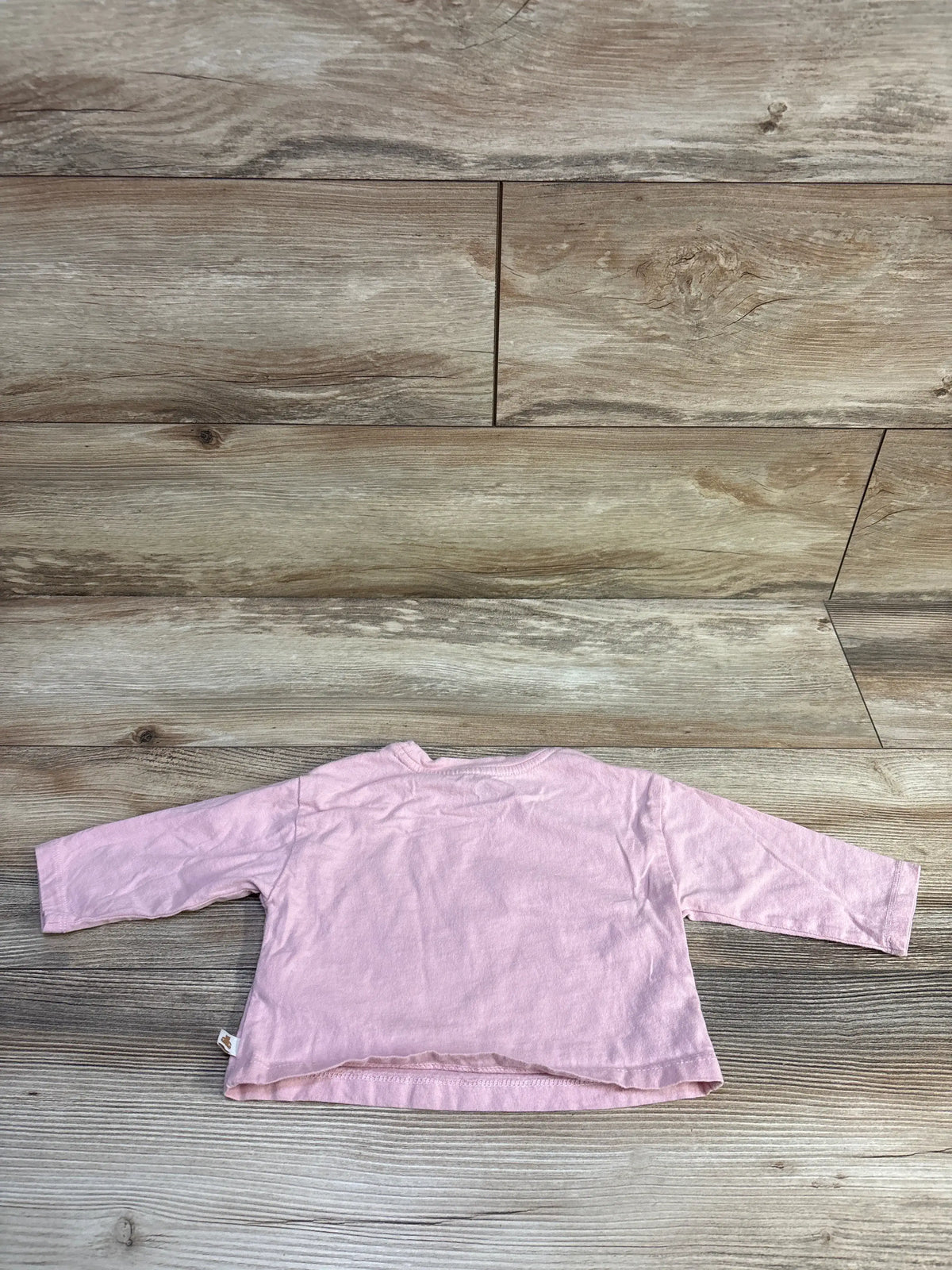 Back view of a pink baby long sleeve shirt by Me n Mommy To Be on a wood background