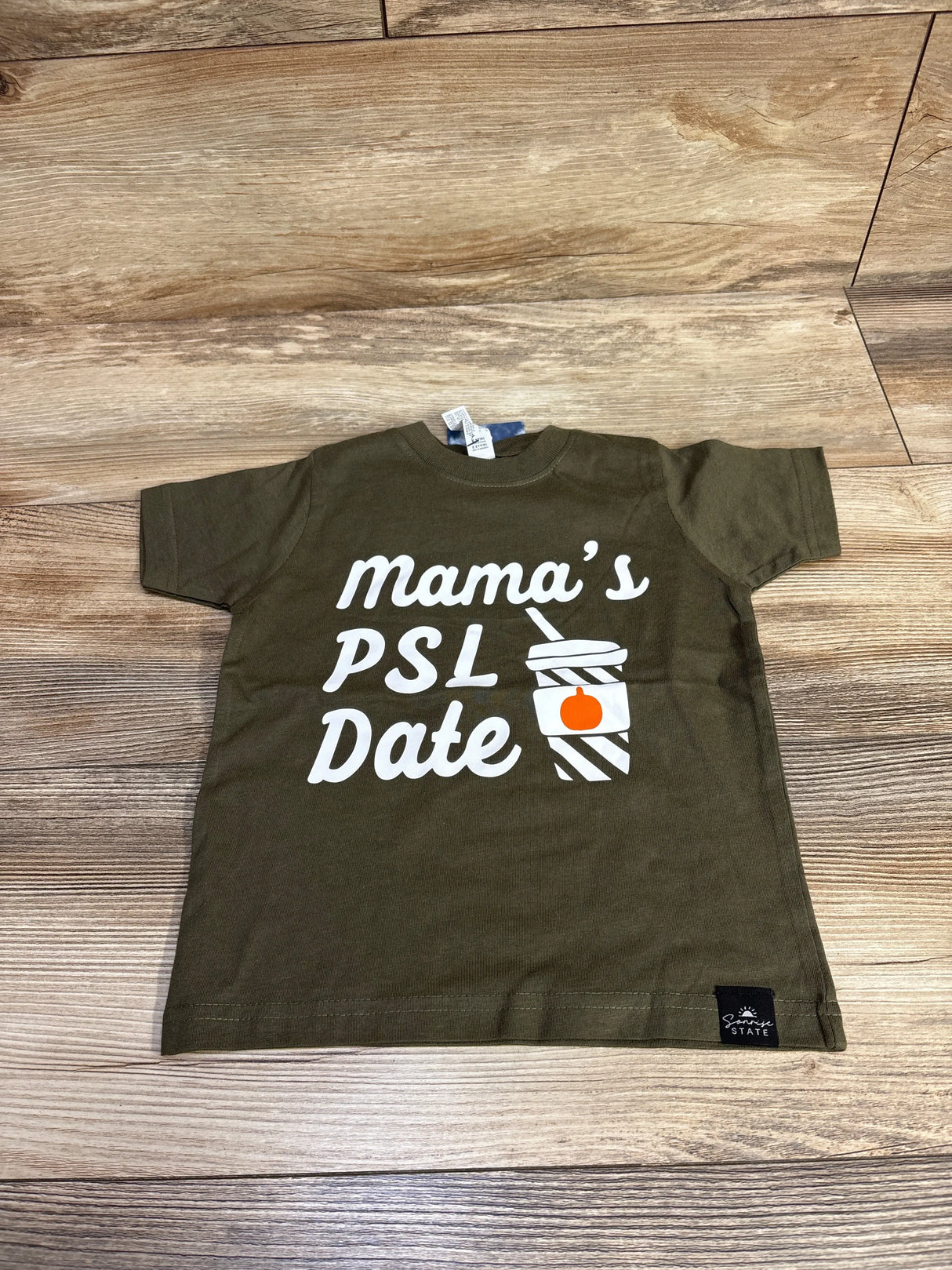 Olive green toddler shirt with 'Mama's PSL Date' and coffee cup graphic on wood floor