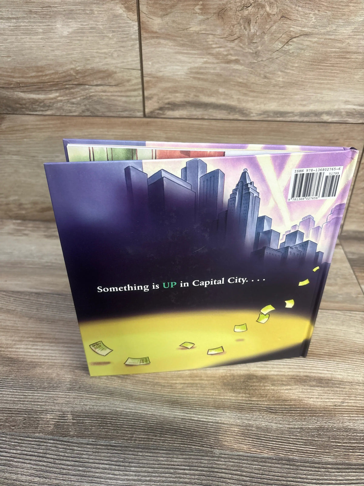 Front cover of The Upper Case hardcover book showing a city skyline and headline Something is UP in Capital City
