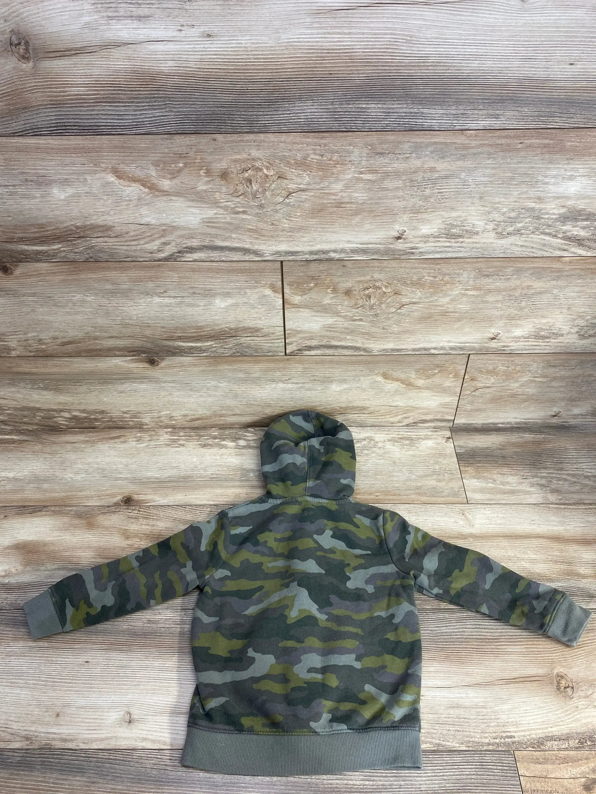 Back view of kids' camo hoodie laid flat on wood floor, children's resale clothing