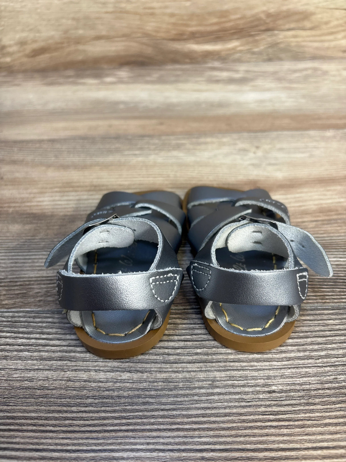 Silver Salt-Water Original sandals, front view, with woven vamp detailing, brass buckles, and brown rubber soles on wood