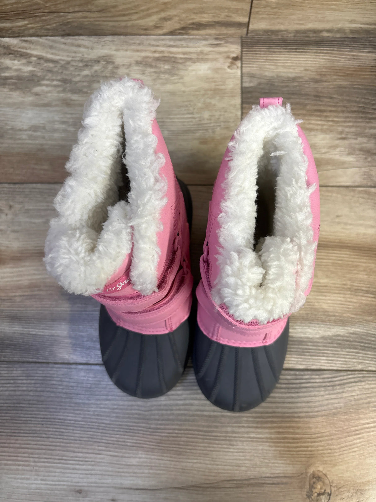 Top-down view of Cat & Jack Denver toddler winter boots showcasing pink upper, black rubber shell and white faux-fur lining on wood floor