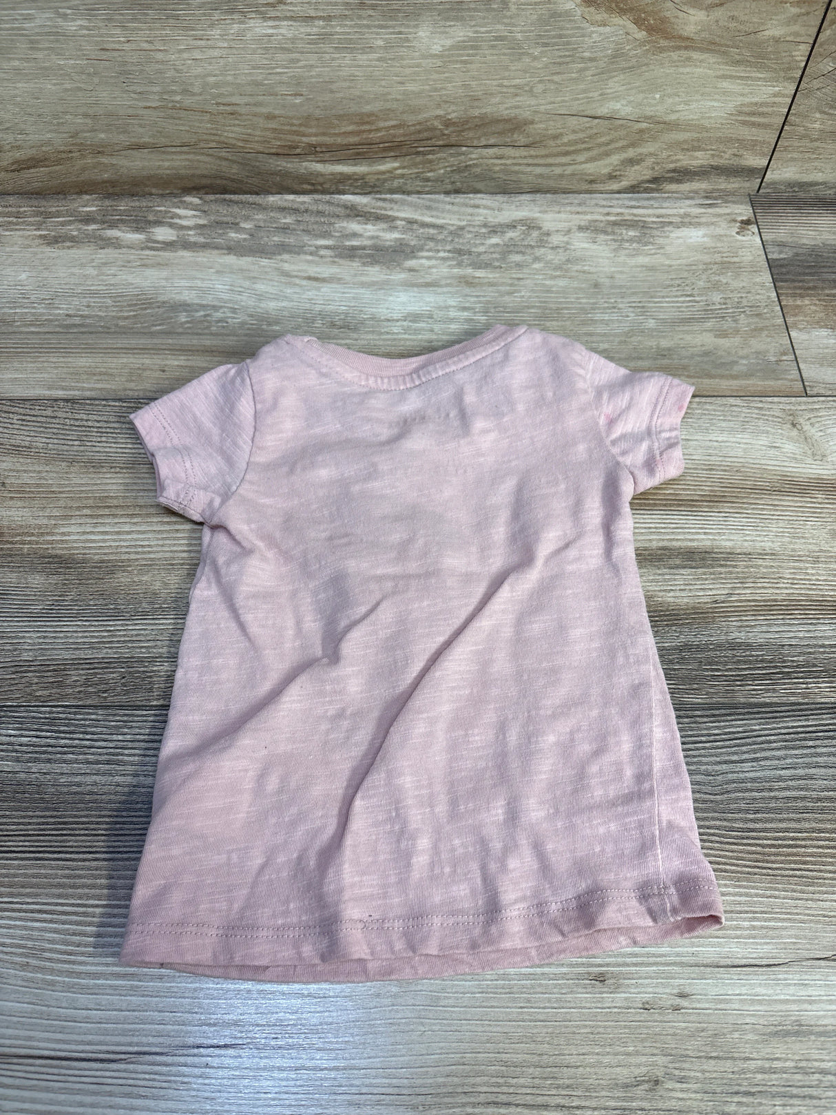 Back view of pink Disney Princess Moana toddler t-shirt size 2T showing short sleeves and plain back on wood floor background