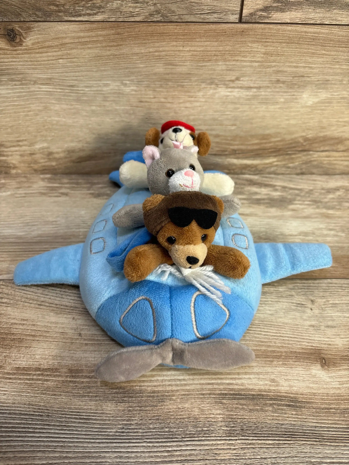Front view of 10-inch Unipak plush blue airplane showcasing three finger puppets including a bear with sunglasses on wood