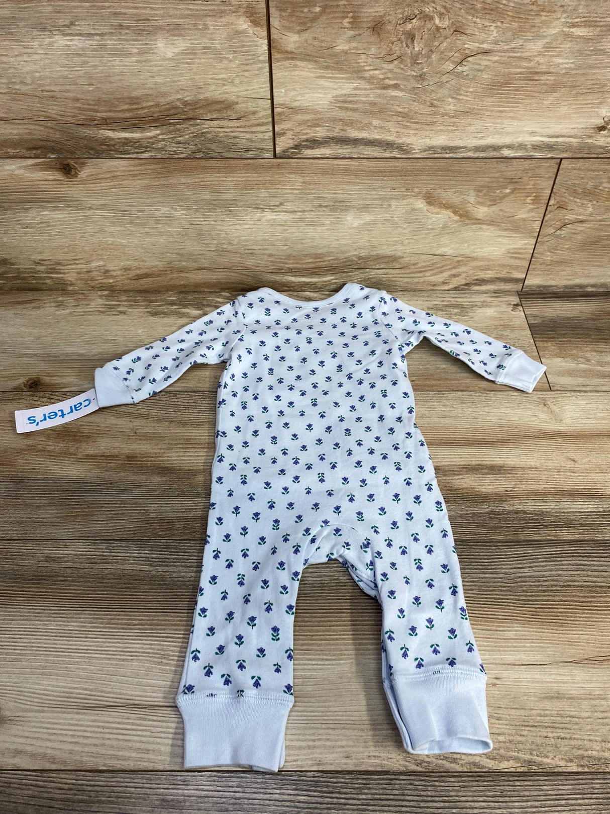 White floral print baby sleeper on wood floor, long sleeves, Carter's label visible