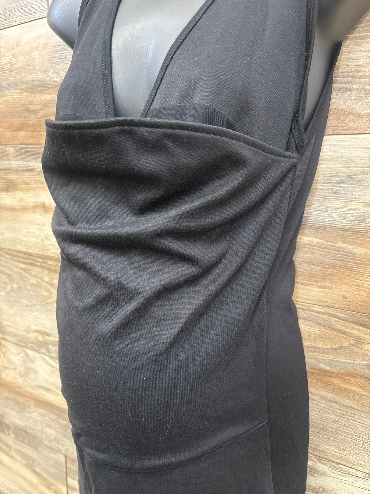Dark gray maternity tank top with ruched side panel, displayed on mannequin over wood floor