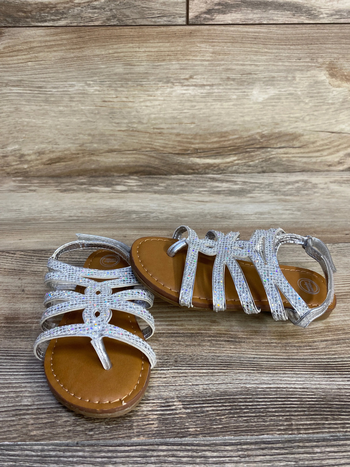 Girls' glitter strappy sandals with tan soles on wood background