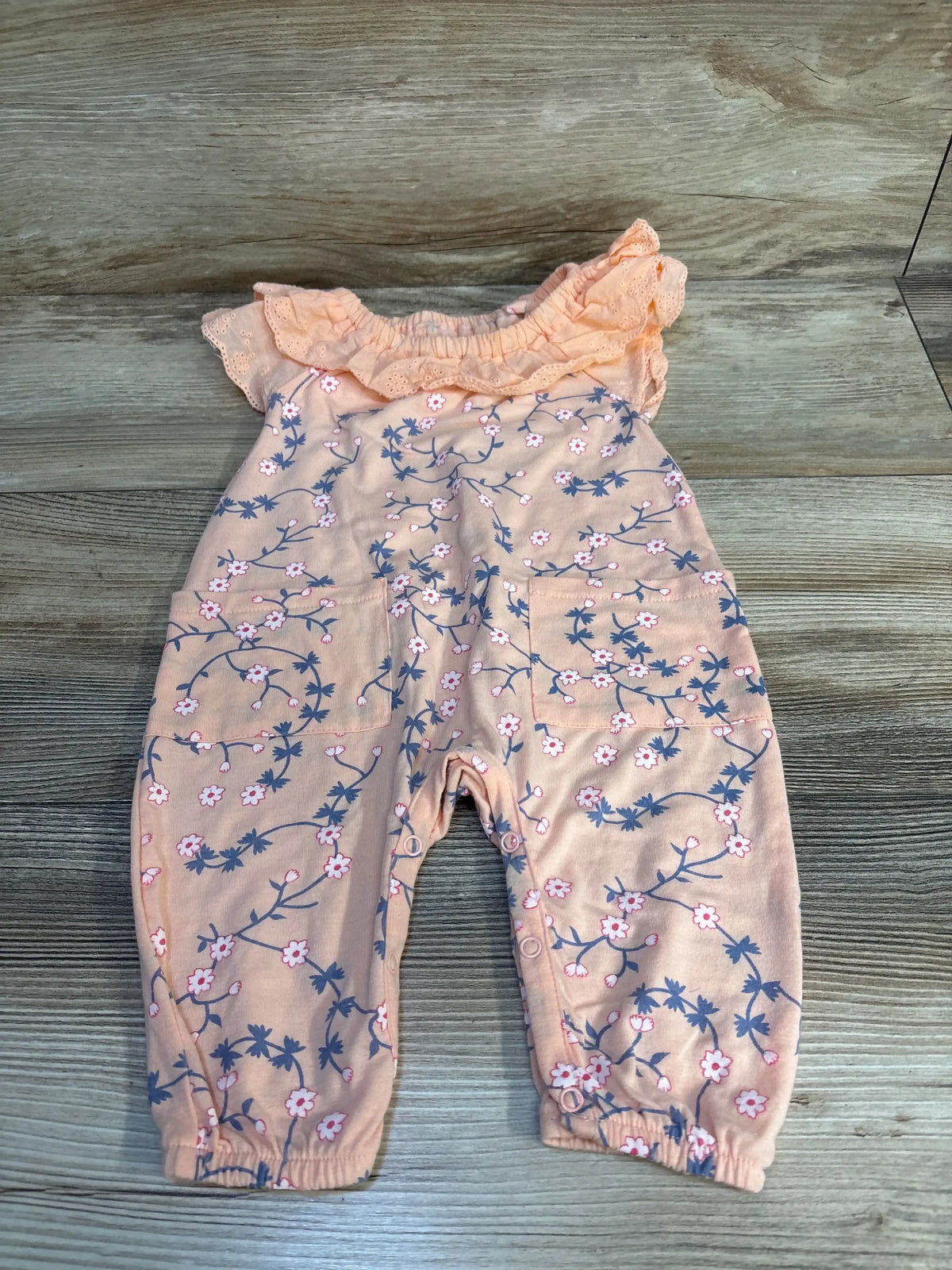Pink floral baby romper with ruffled sleeves and snap closures, ideal for infants and toddlers.