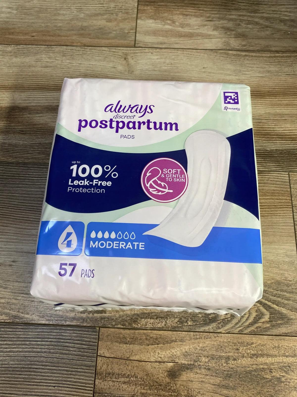 Front view of Always Discreet postpartum pads, moderate absorbency, 57 count, 100 percent leak-free on wood floor