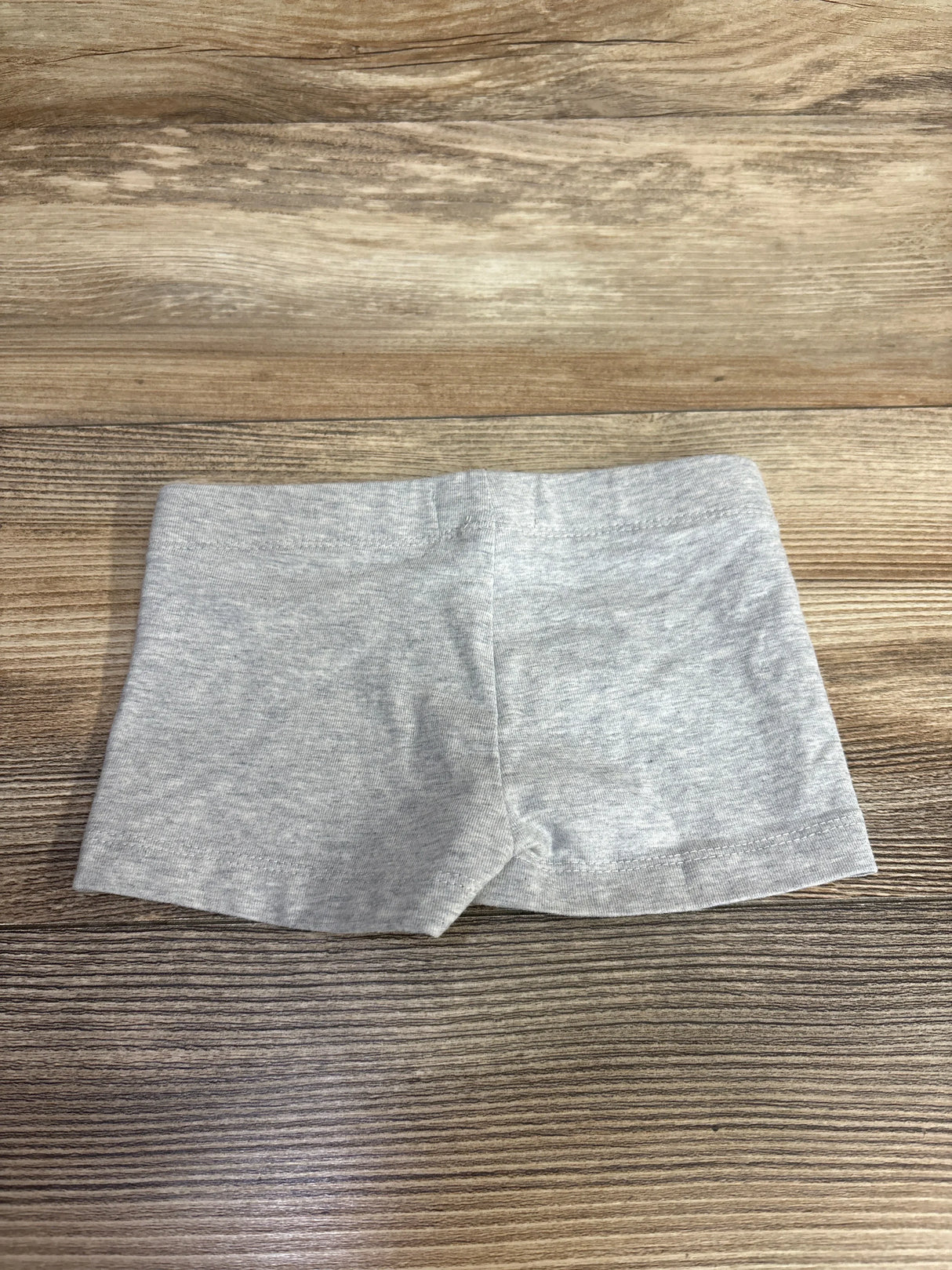 Light gray toddler shorts on wood background, kids clothing, comfortable cotton apparel