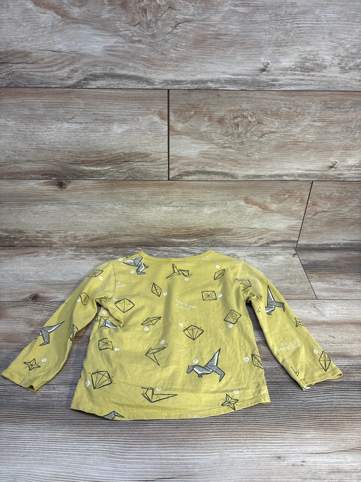 Yellow long sleeve shirt for kids with origami animal and shape prints on wood background