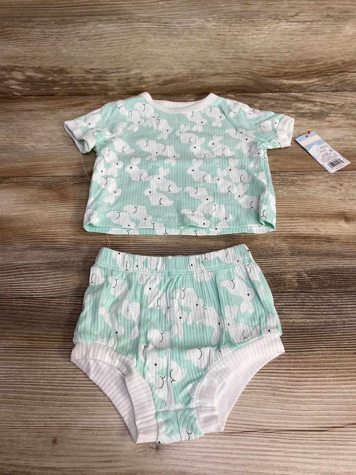 Flat lay of mint ribbed shirt and shorts with white bunny print, elastic waist and short sleeves on wood background