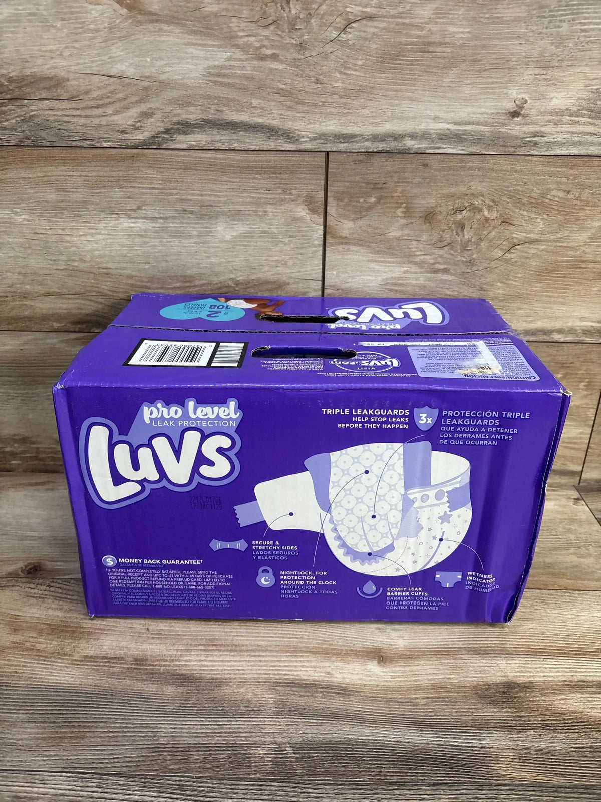 Front view of NEW Luvs Diapers 108ct Size 2 package showcasing triple leak protection on a wood floor