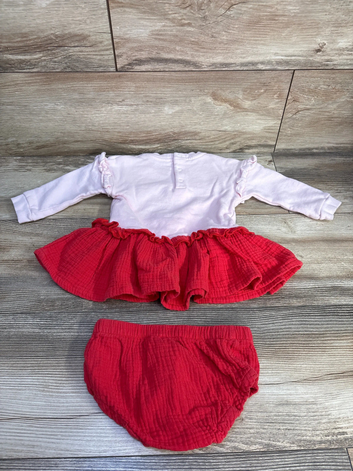 Front view of pink Disney Store Minnie Mouse gauze sweatshirt dress and matching bloomers with ruffled details on wood floor