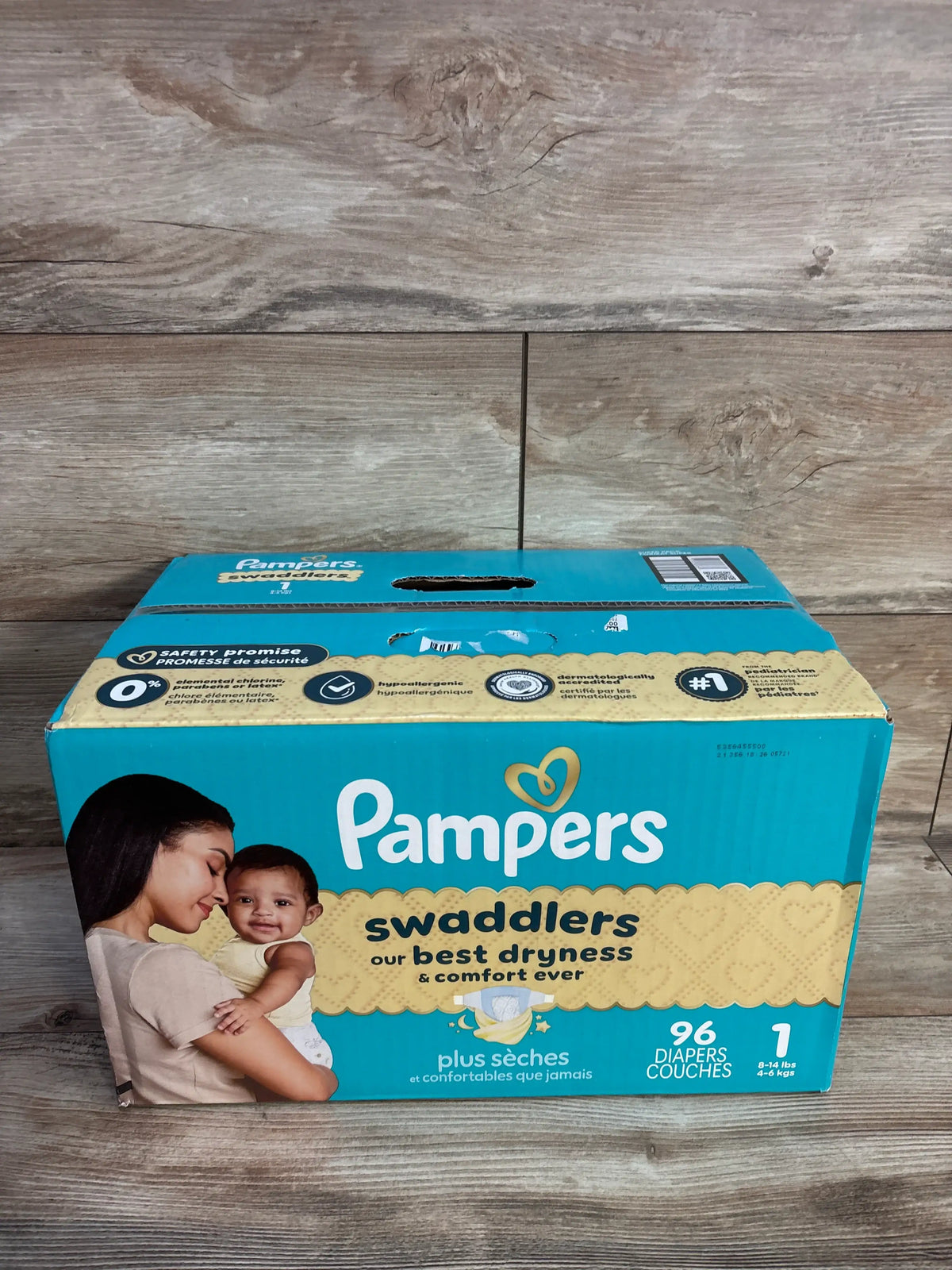 Front view of NEW Pampers Swaddlers diapers Size 1 96ct box with 96 diapers and 8 to 14 pound fit on wood floor