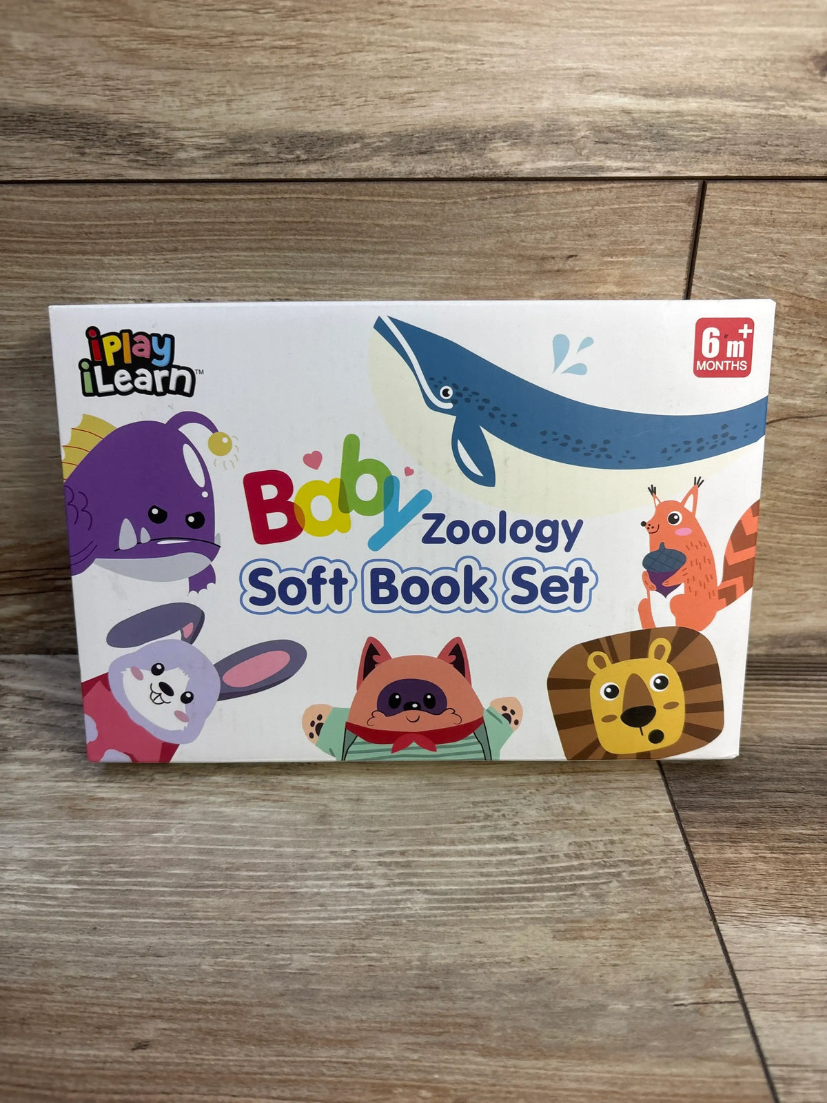 Front view of iPlay iLearn Baby Zoology soft book set with colorful animals and 6 months label on wood background